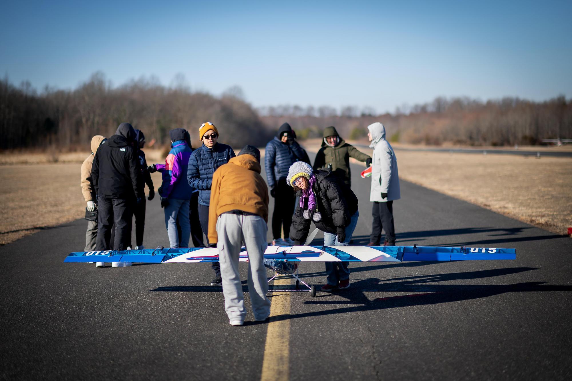Students gather on a runway before the launch of Penn’s aerial drone plane.