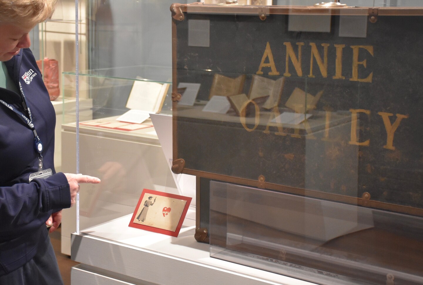 Penn-Libraries-Regan-Klastrup-with-Annie-Oakley-souvenir-card-in-exhibition-on-women-in-the-American-wilderness