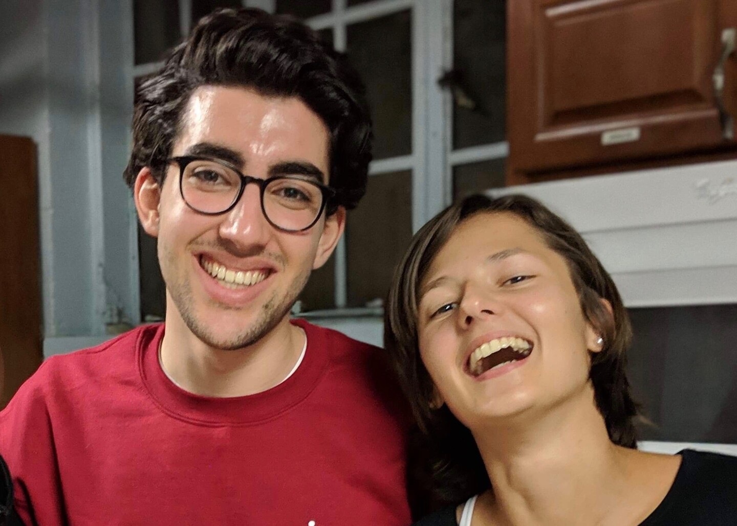 Two students looking at the camera, smiling and laughing. 