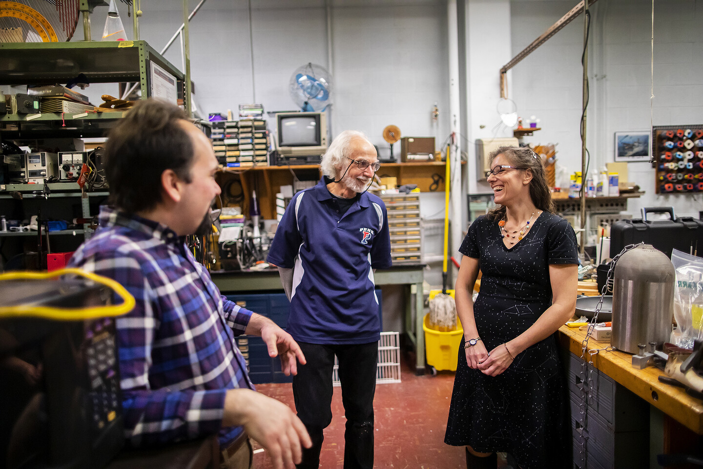 harnish, berner, and marcopul laugh together while standing in a room full of tools and equipment