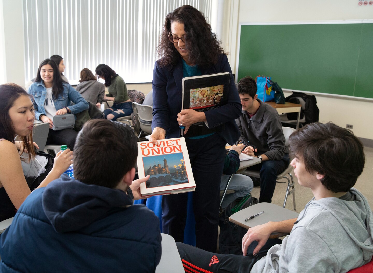 Kristen Ghodsee handing books out to students in class