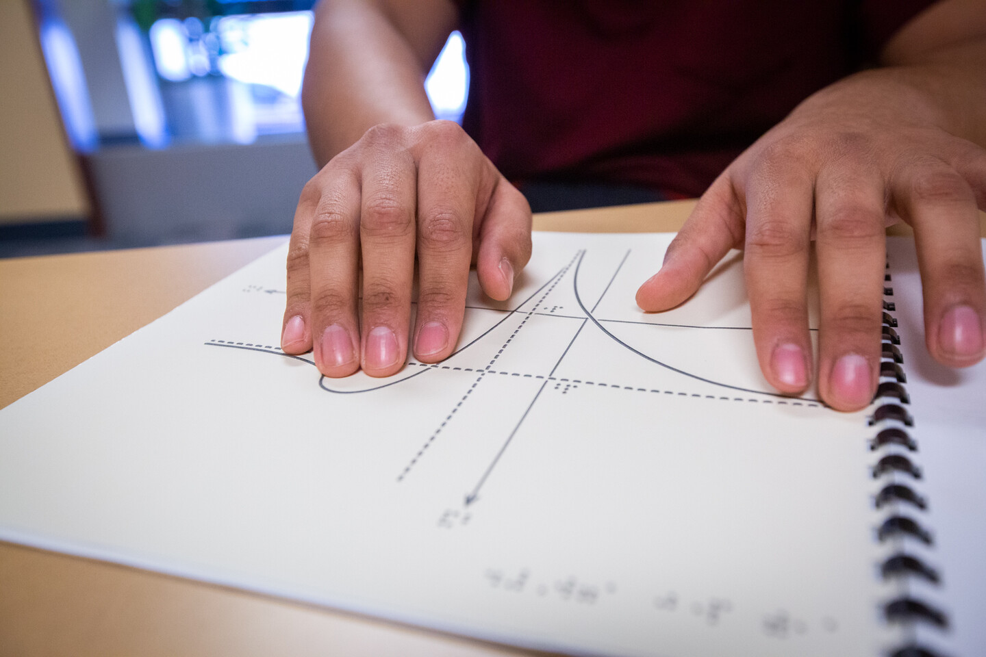 Carlos Garcia's fingertips read a braille graph.