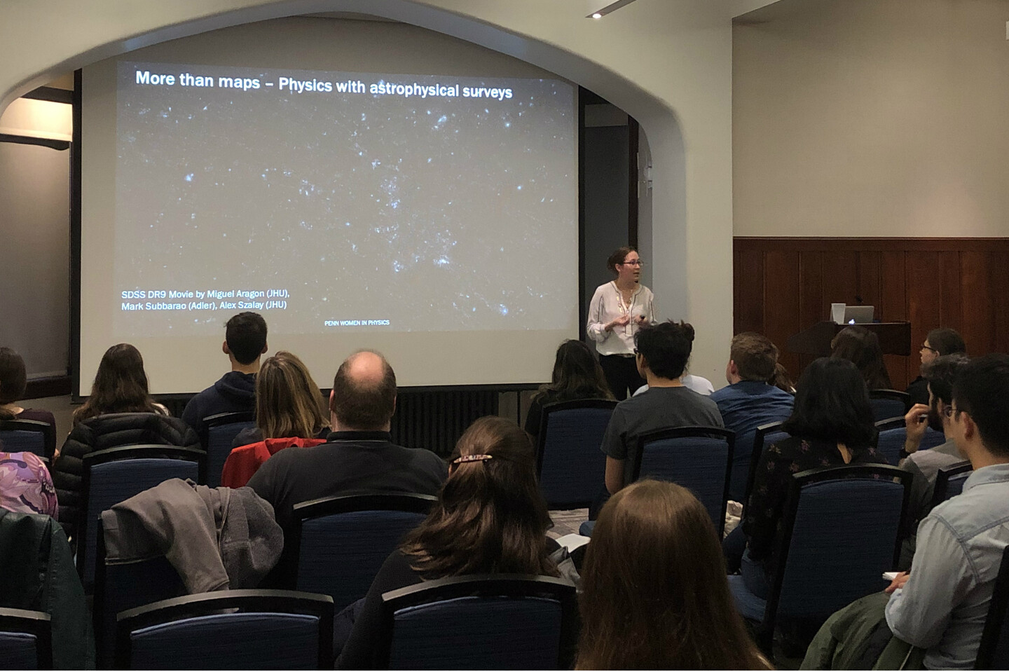 willman in front of a large screen presenting to a group of people