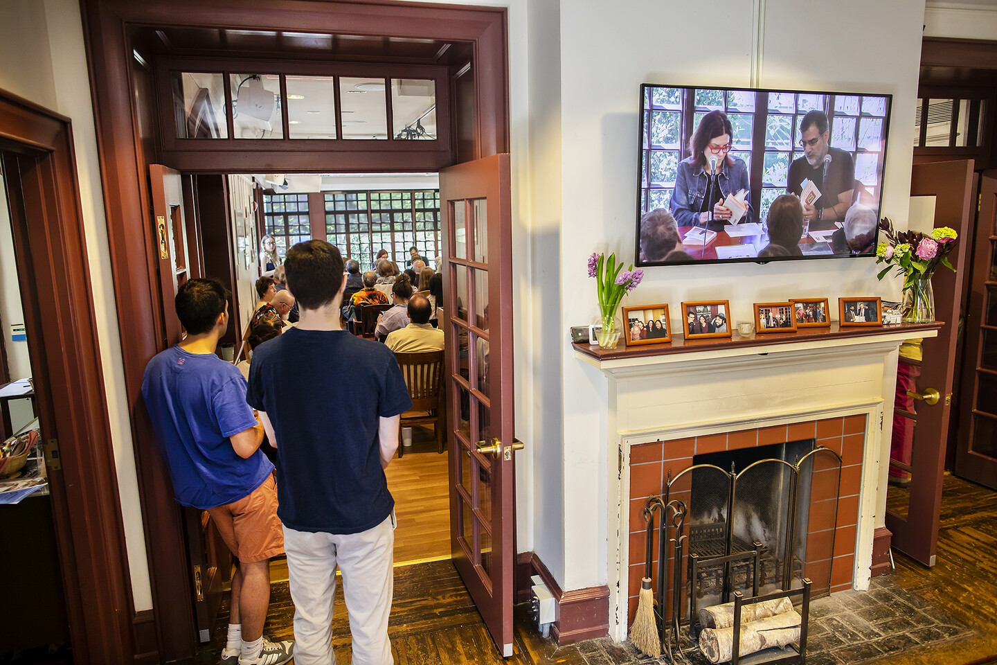 View of the room from the back showing every chair full and people standing. 