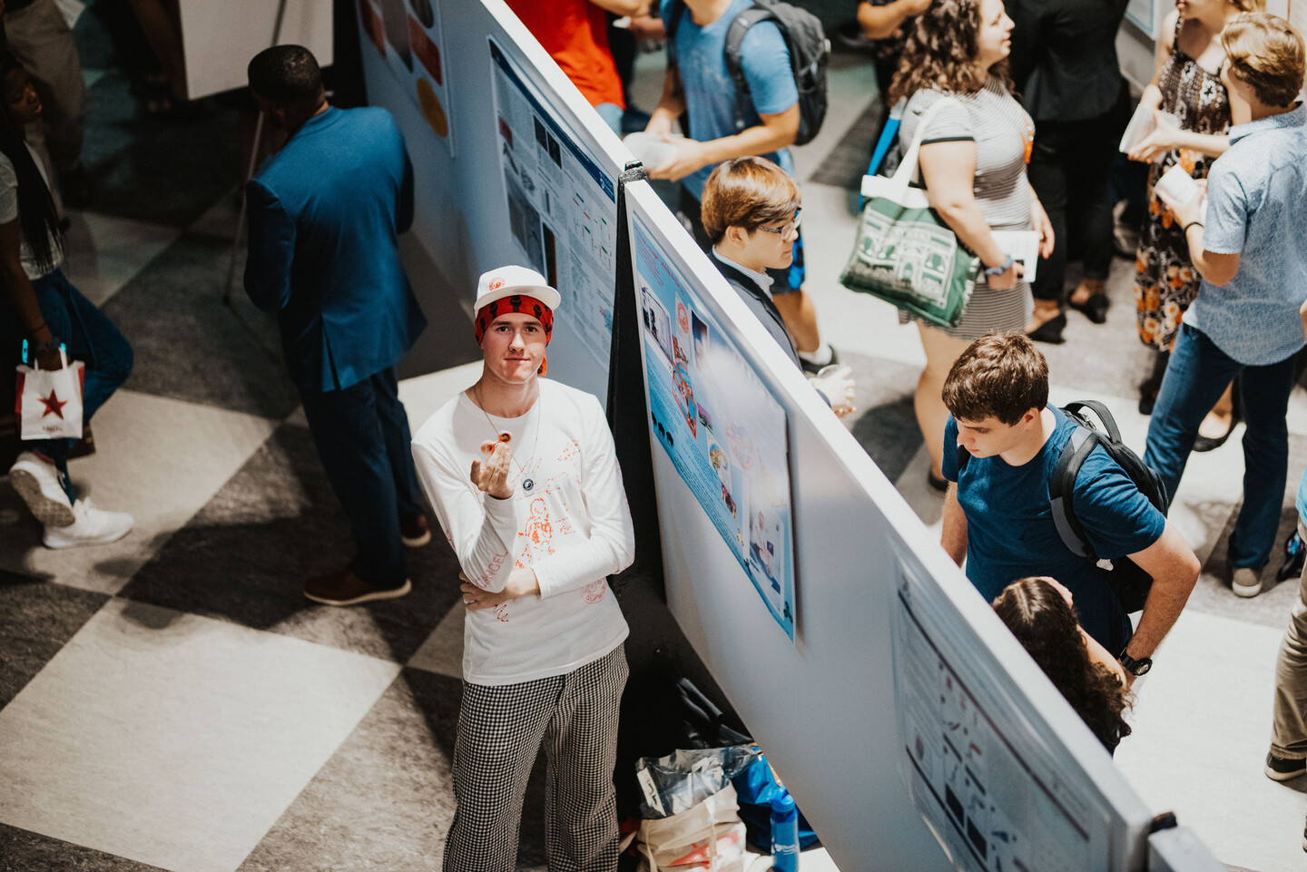 Student standing by research poster with several other students nearby. 