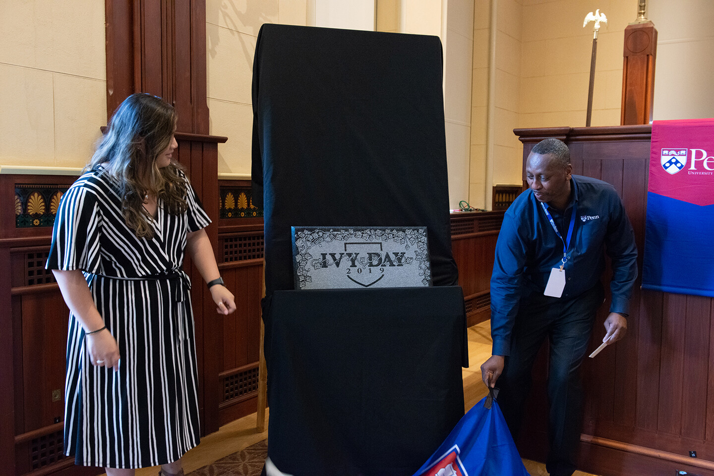 Camille Rapay stands nexts to the Ivy Day 2019 Stone as it is unveiled by a person pulling off a fabric cover.