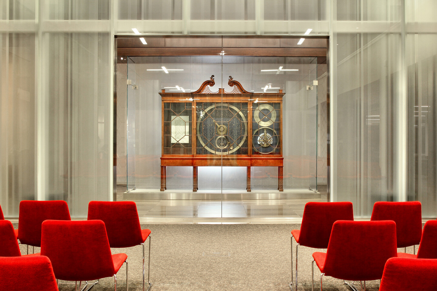 the orrery in a wooden cabinet at the far end of a room full of chairs