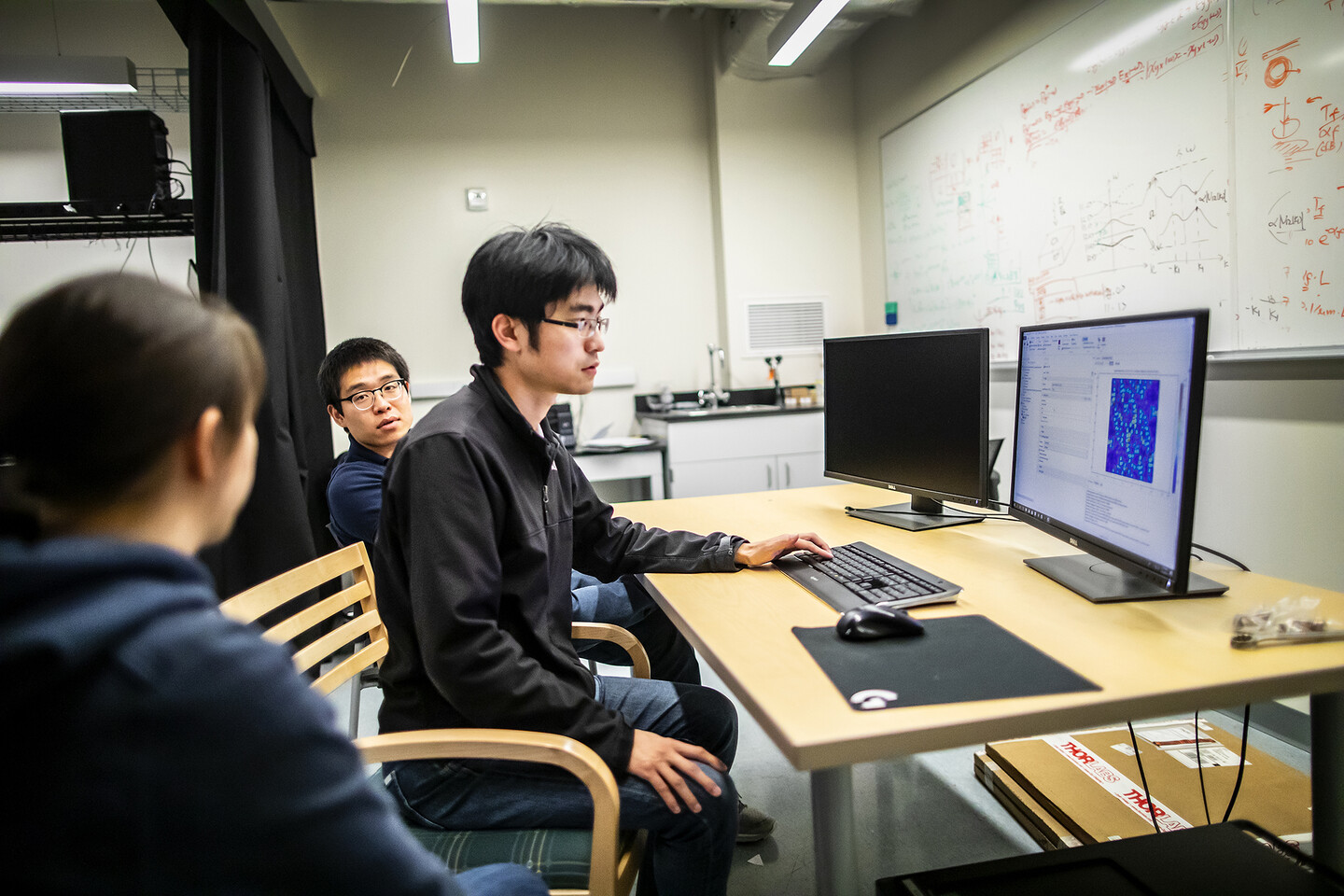 people working on a computer with a white board in the background