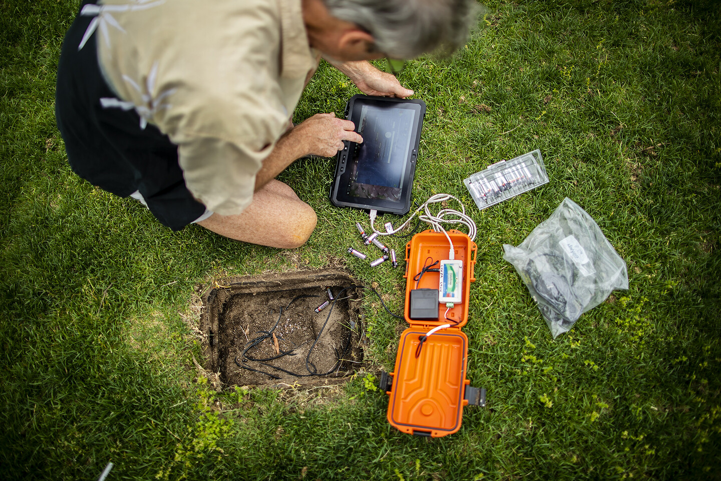 Looking down at a scientists recording data from an orange container containing scientific equipment