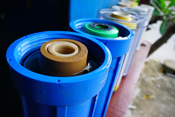 a line of cylinders with used water filters on a bench outside