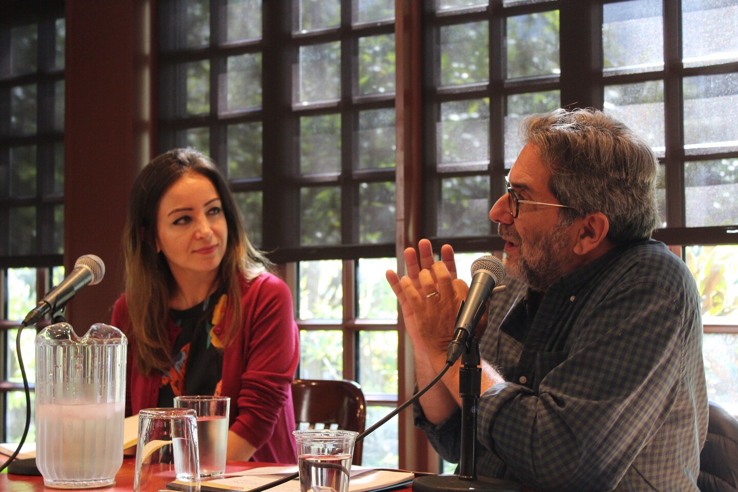 Two people at a desk talking into microphones. 