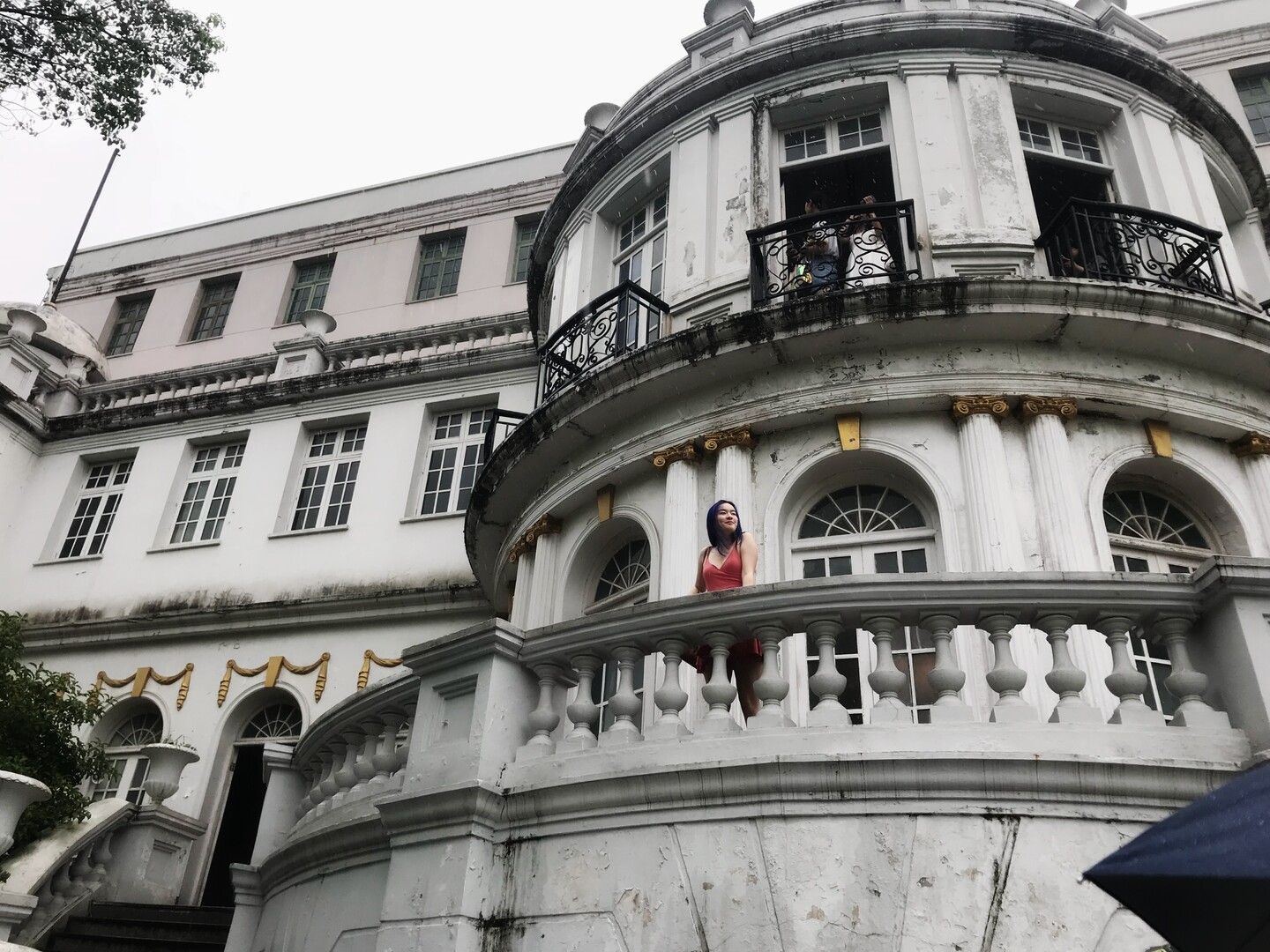 Student standing on balcony of ornate stone building.