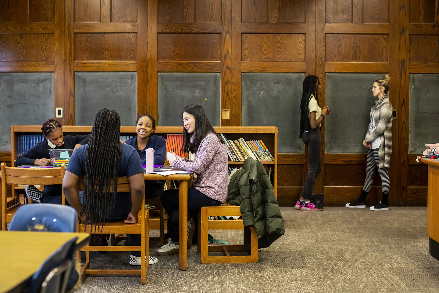 students and mentors gathering a room at a table and standing