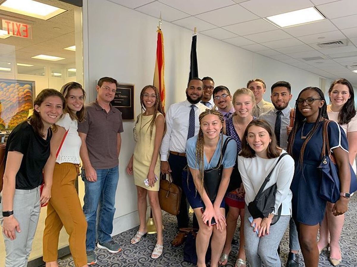 Group of students stands in front of two flags at the U.S. Senate