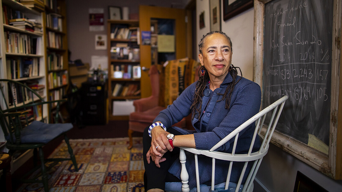 Lorene Cary sits in a chair in her office beside a chalkboard