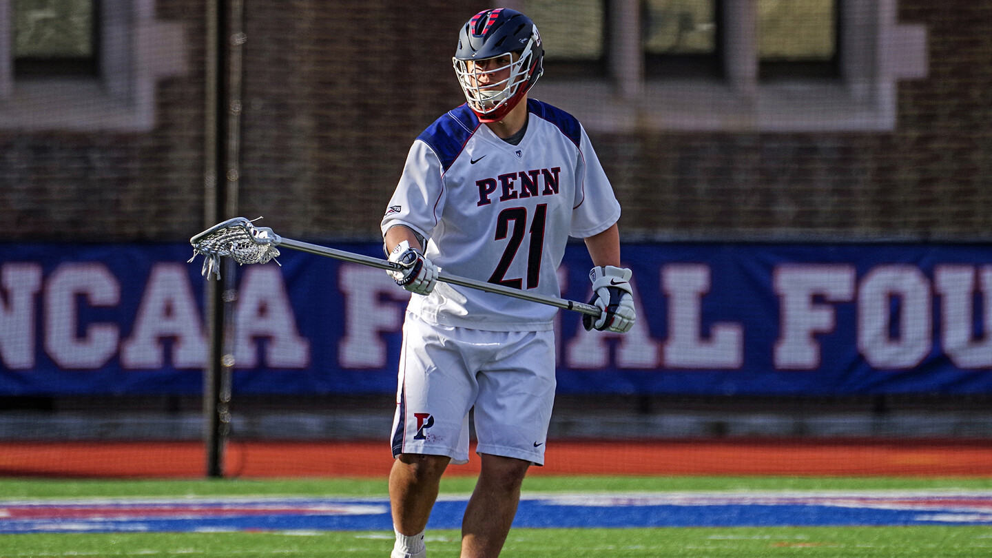 Evanchick walking and pointing lacrosse stick toward the field