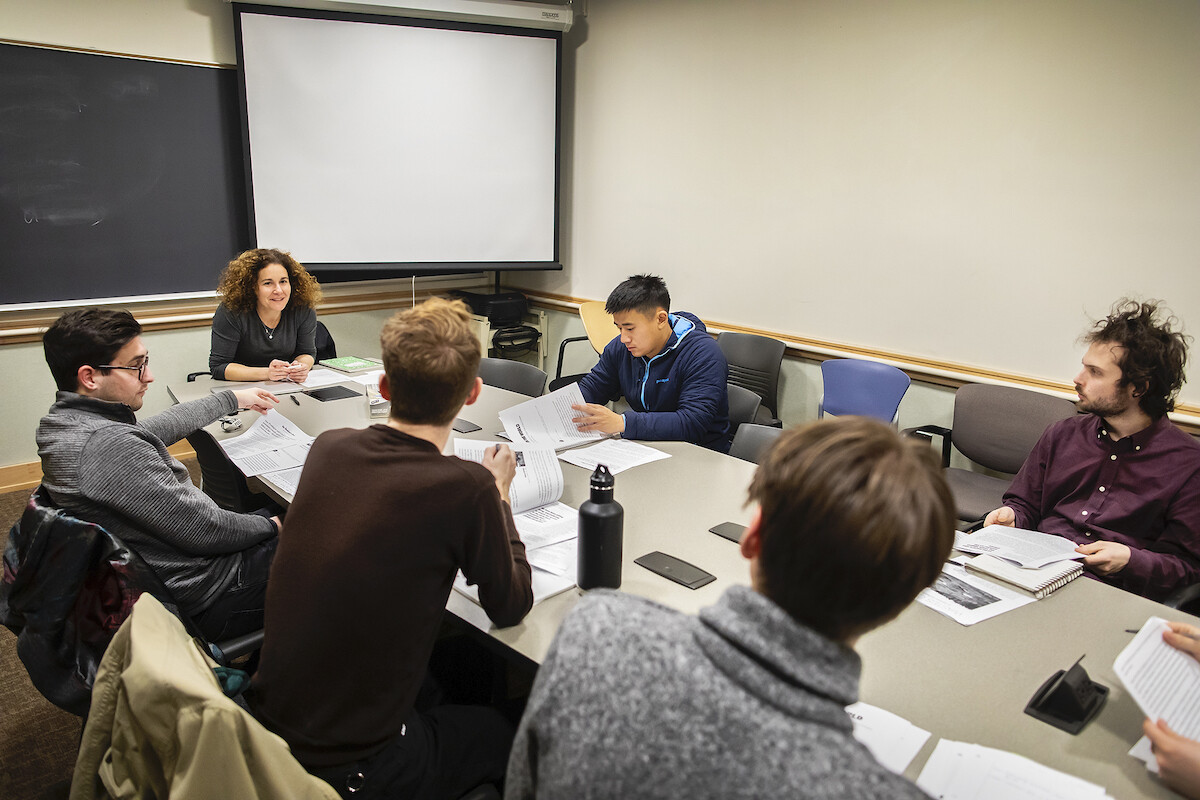 People sit around a conference table, looking at papers and talking.