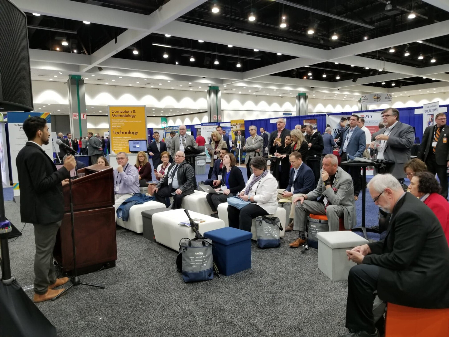 Nikil at a podium speaking to a group of people at a conference