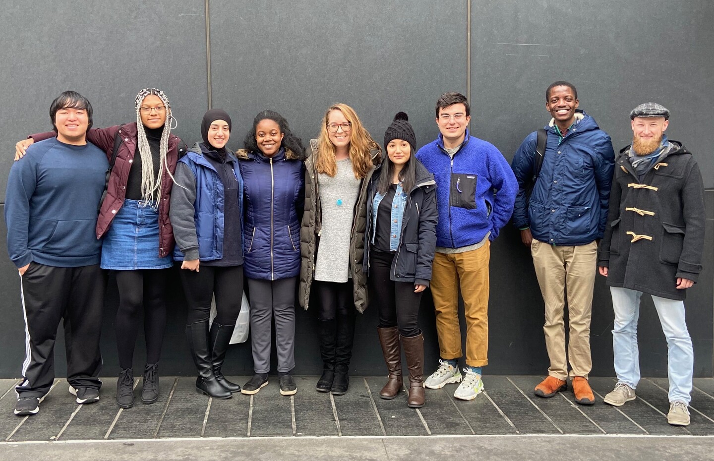 Nine people standing side-by-side smiling 