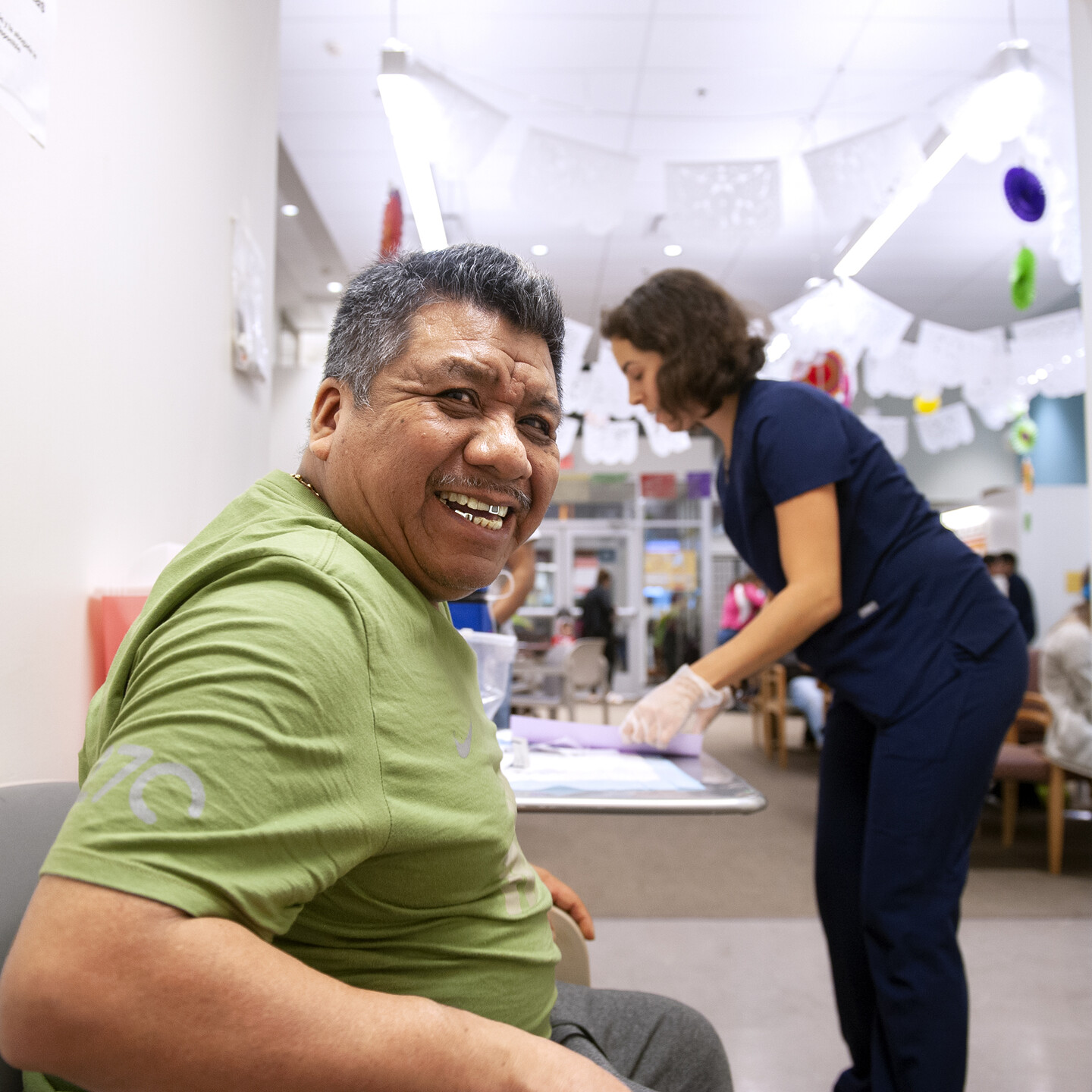 patient looking at the camera and smiling, nurse in background