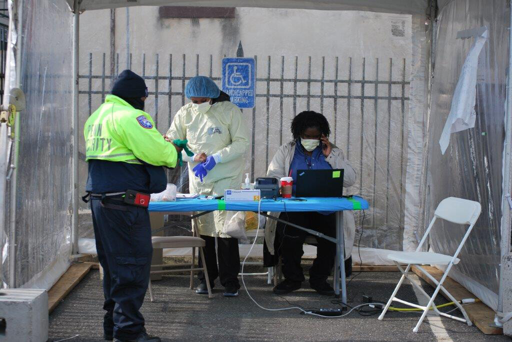 COVID-19 testing site on Penn campus with nurses and Penn police under a clear tent and folding table set-up