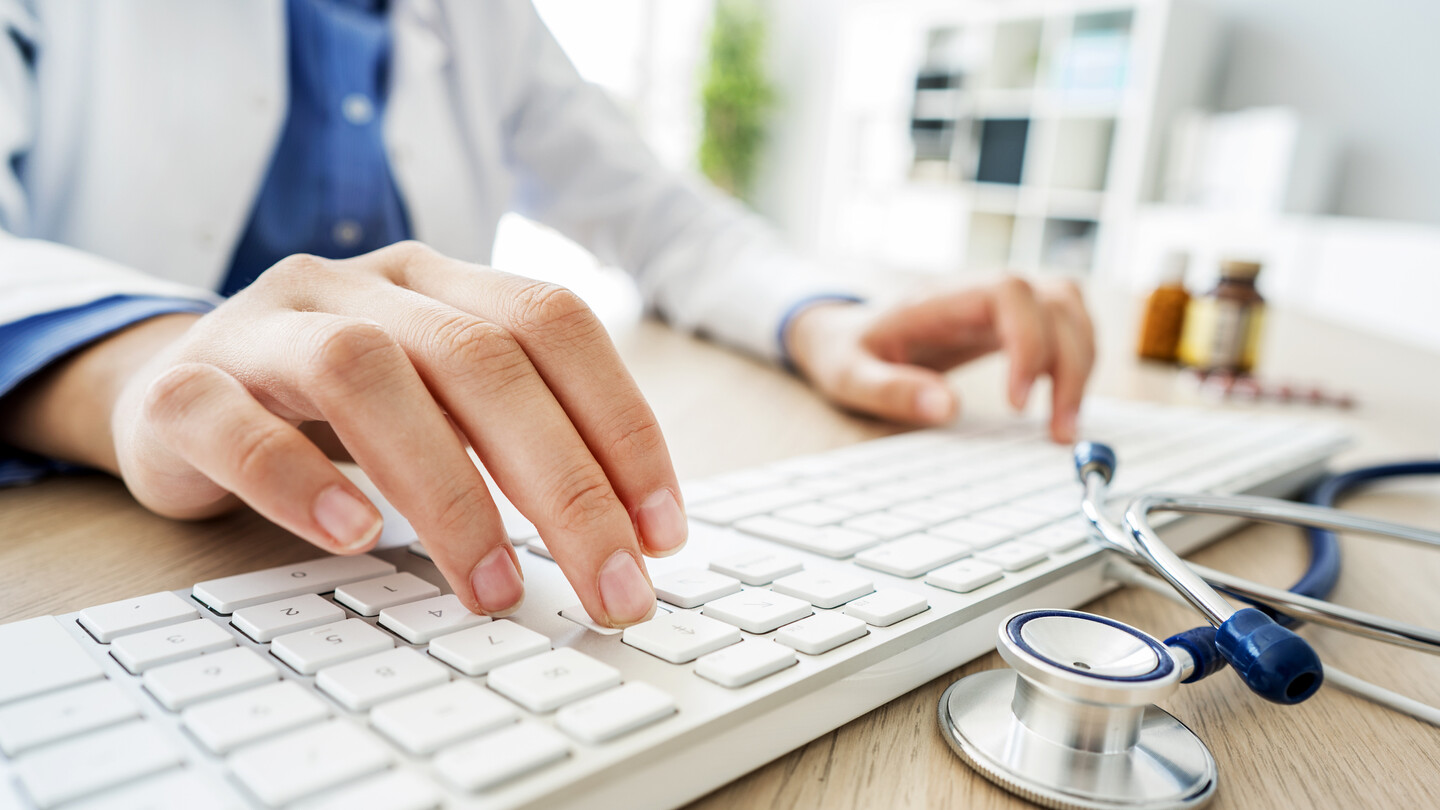 a doctor's hands typing on a keyboard