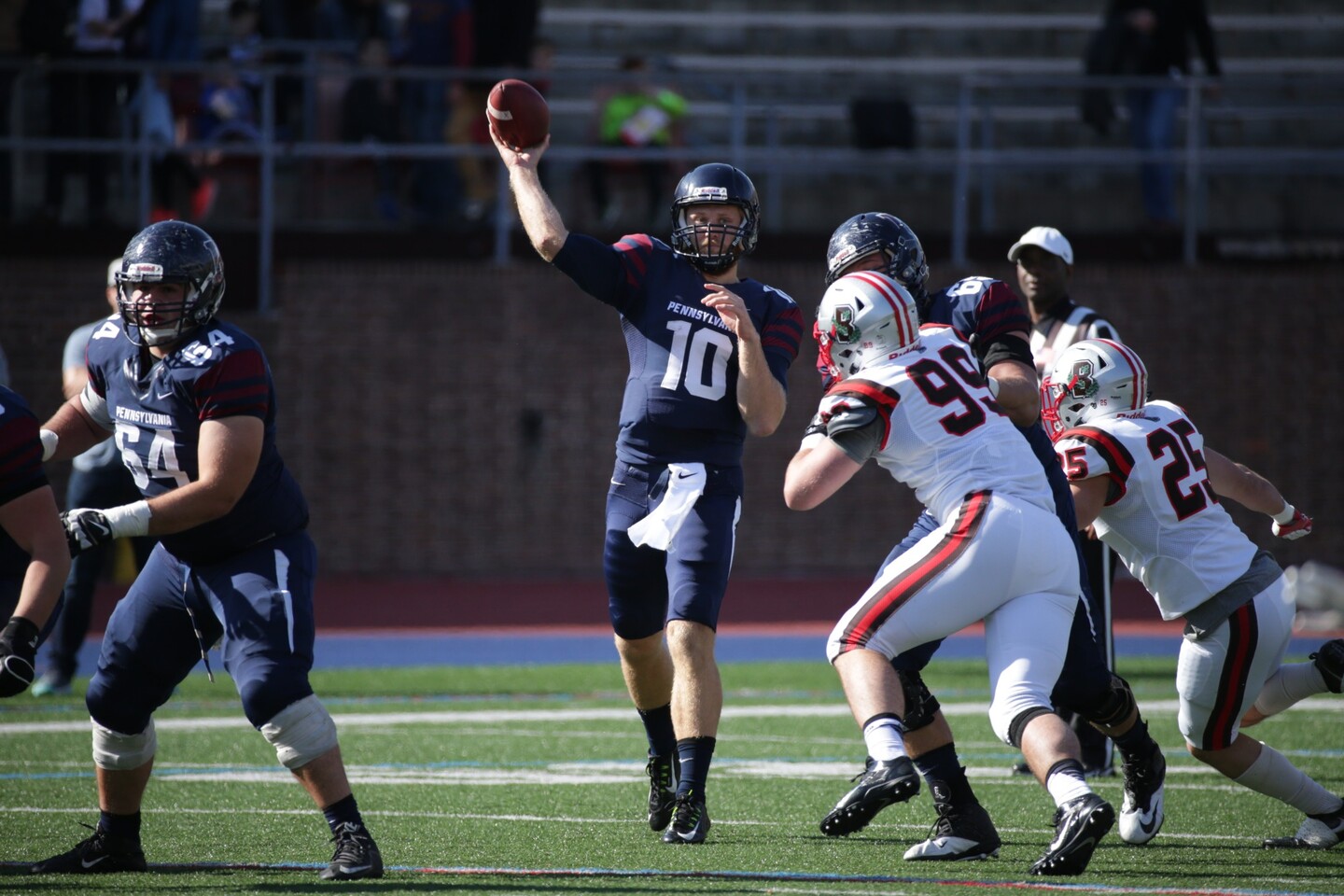 Quarterback Alek Torgersen throws the ball down the field during a game, while being rushed by two defensive players.