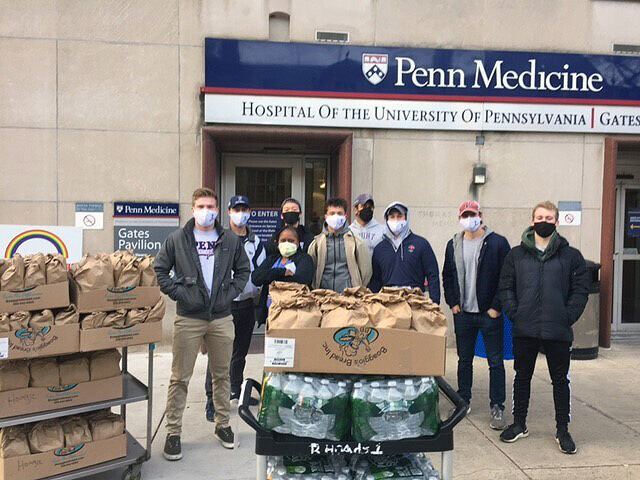 Members of the sprint football team stand outside of HUP with bags of food and bottles of water.