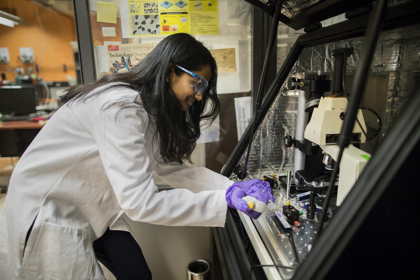 a person pipetting onto a device in a glass hood