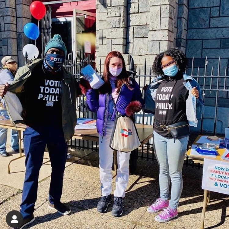 Three people outside with wearing shirts saying vote today Philly