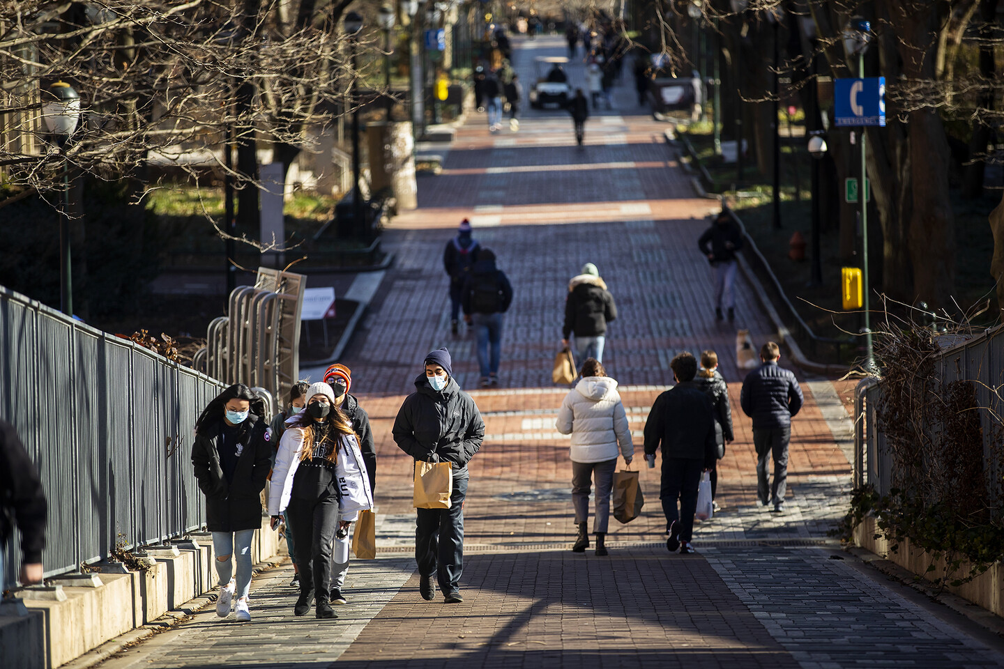 students wearing masks walking across locust walk bridge