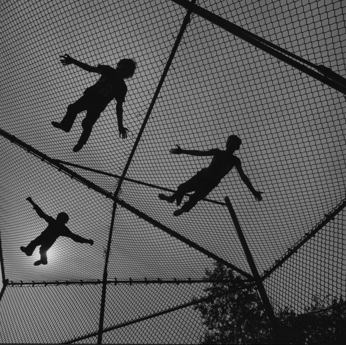 Three people's shadows on chain link screen