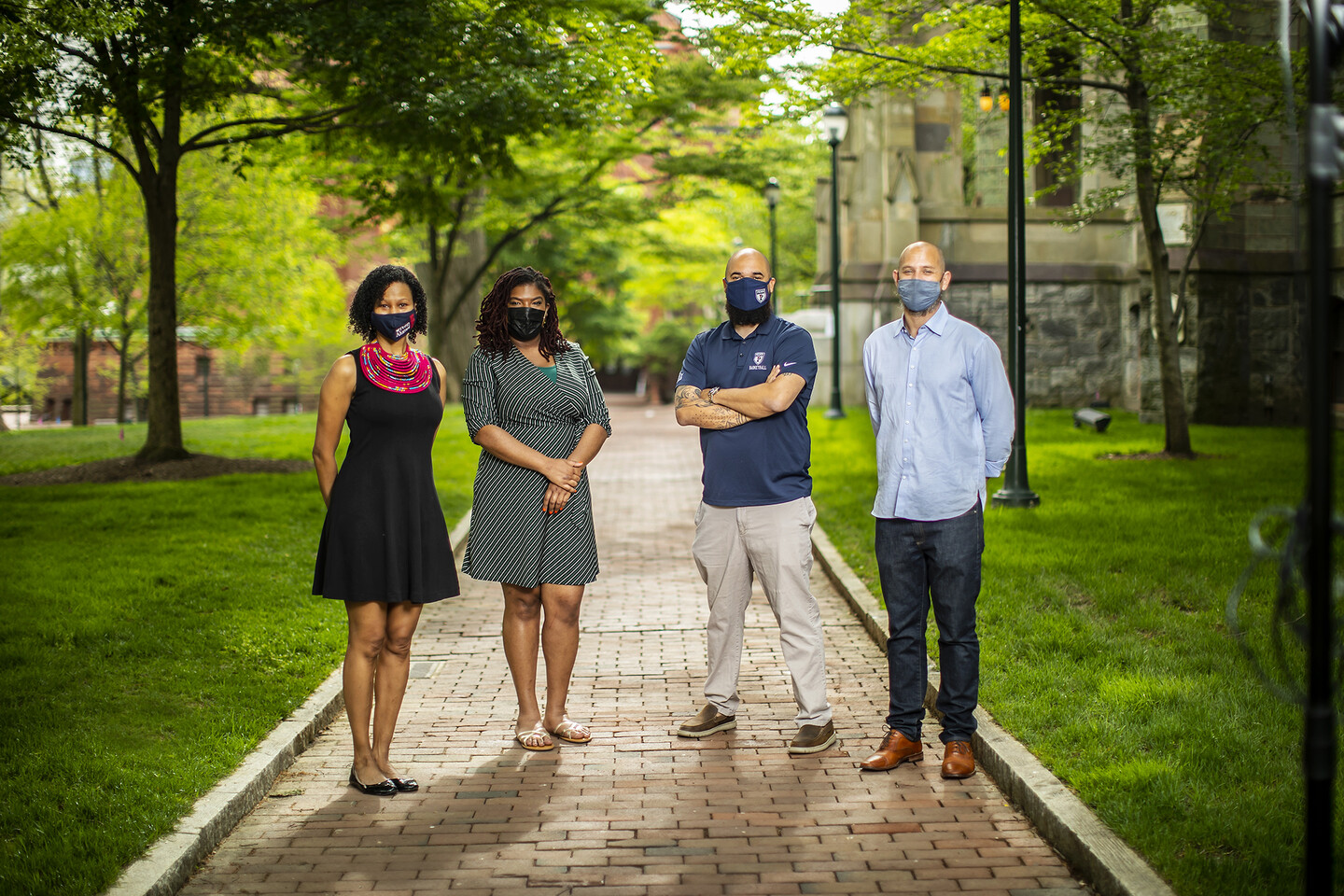 four people standing outside on a brick sidewalk 
