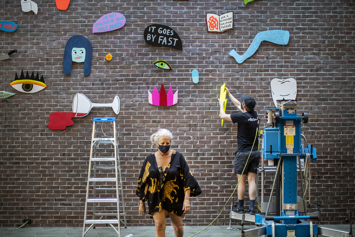 Martha Rich walks away from brick wall filled with art