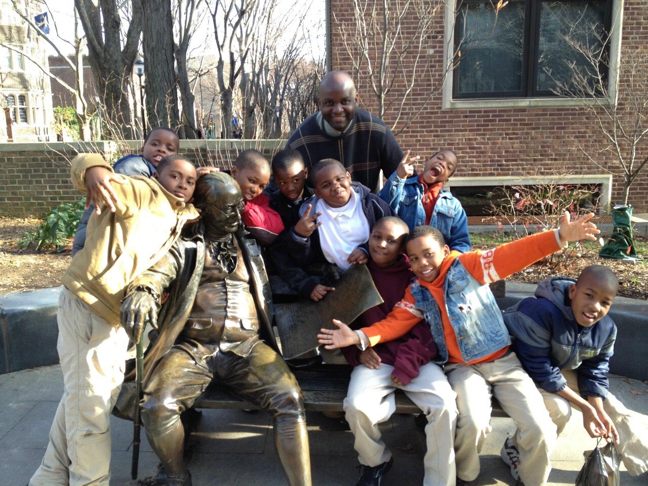 kids and an adult pose with Ben on the Bench on Penn's campus