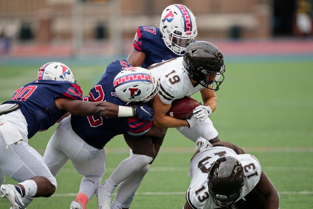 Penn football players tackle a Brown player.
