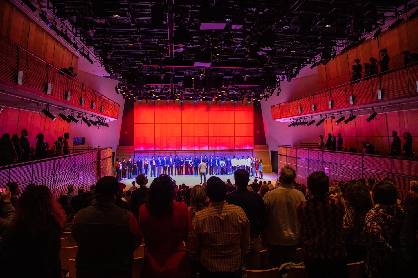 several students on stage singing with many people in the audience 