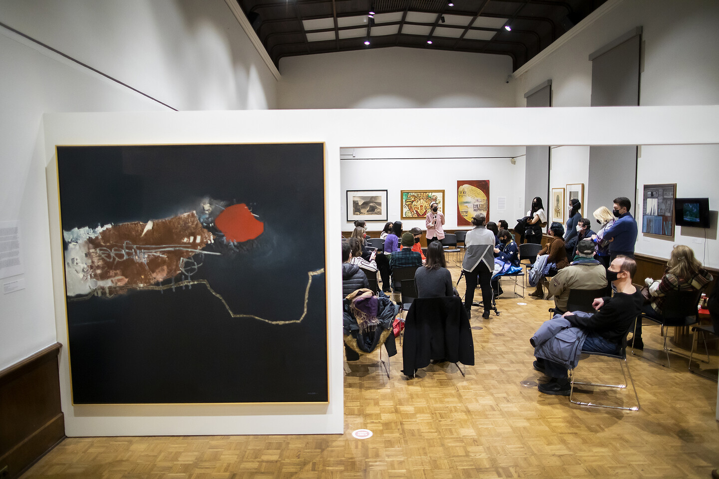 oil painting on wall with people sitting in chairs in art gallery