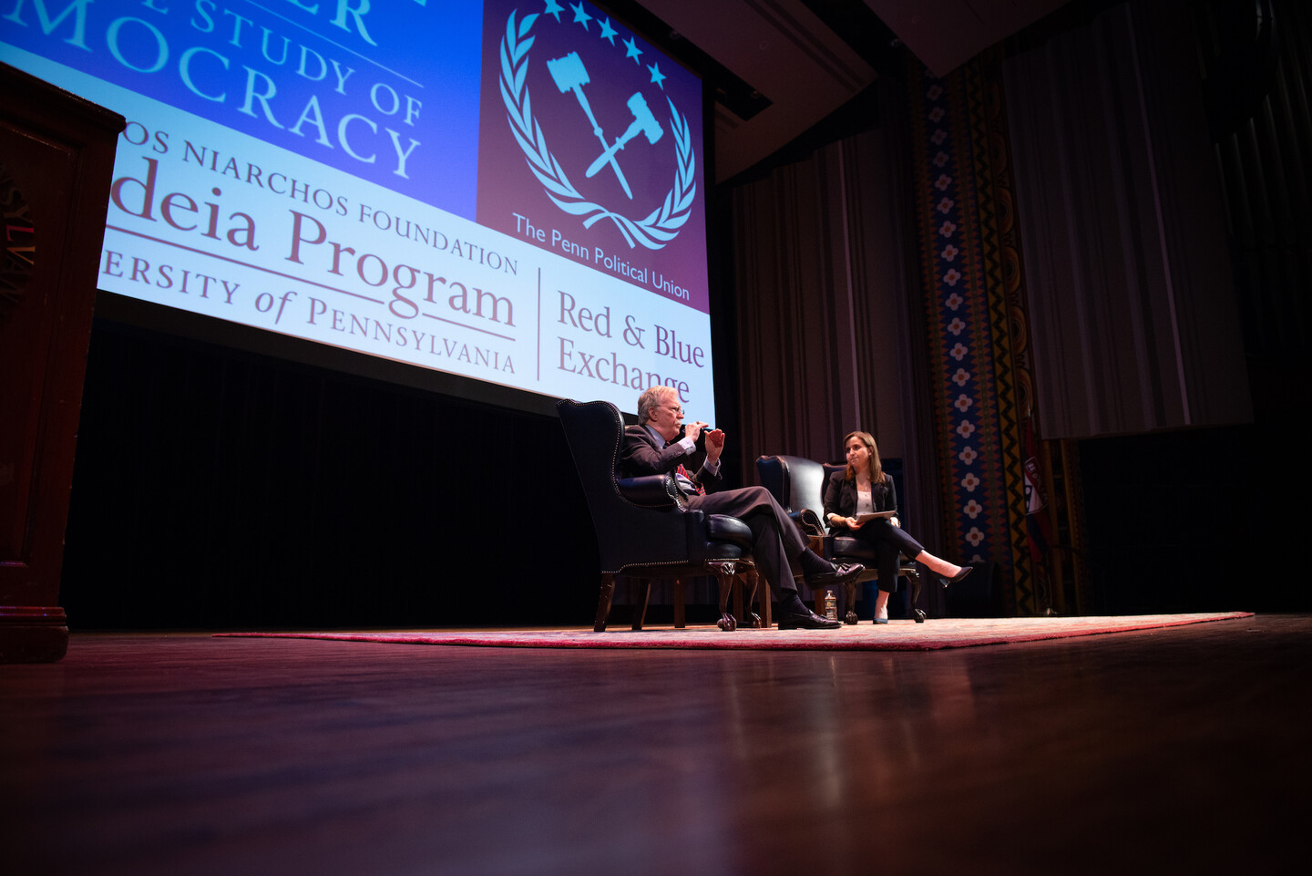 John Bolton sits on a stage at Irvine Auditorium with the president of the Penn Political Union