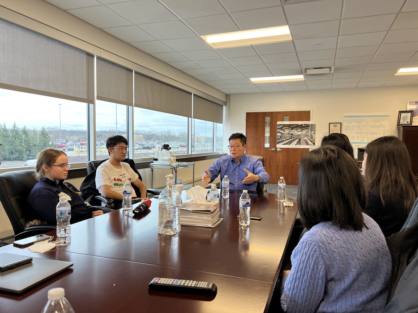 People seated at a conference room table with water bottles and books.