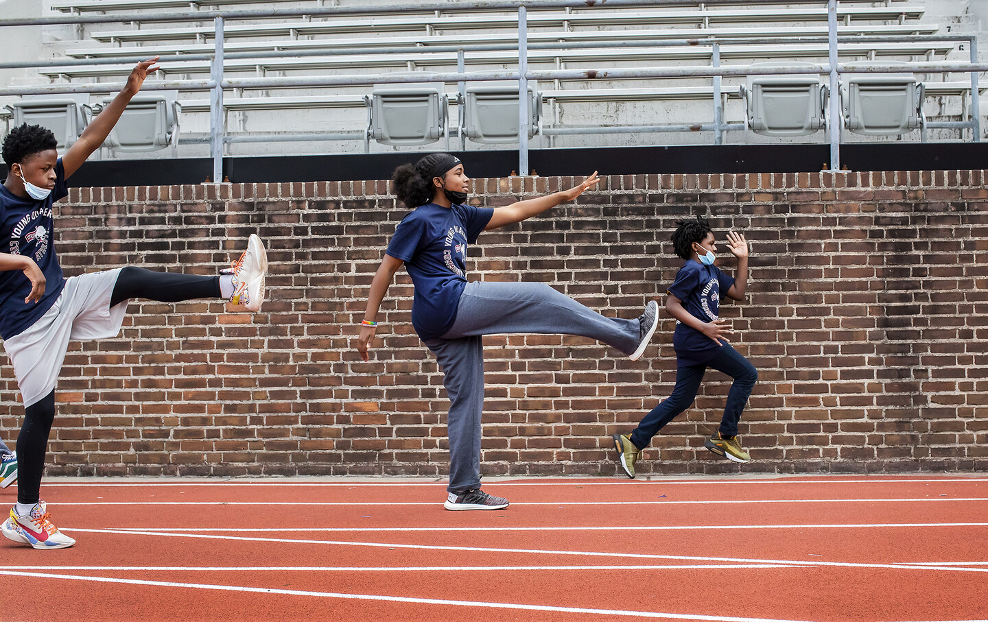 Three students stretch their arms and legs out front