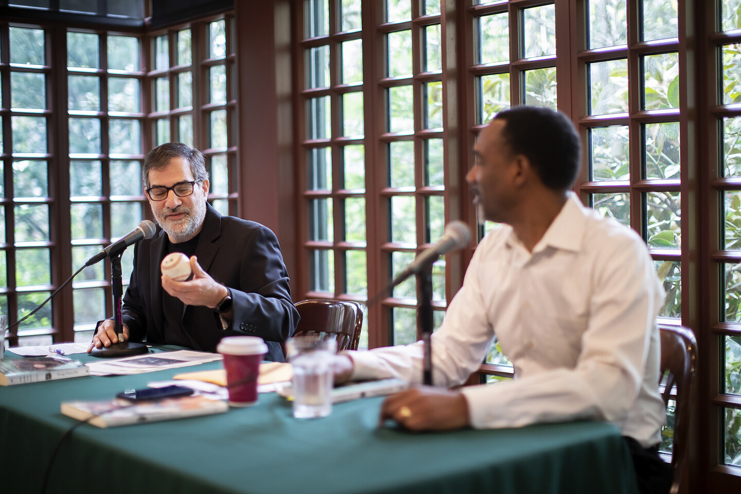 Al Filreis holding baseball while sitting at a table with Doug Glanville