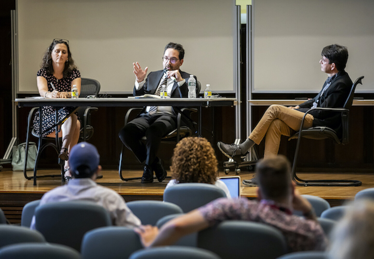 Three people sit on a stage at a table