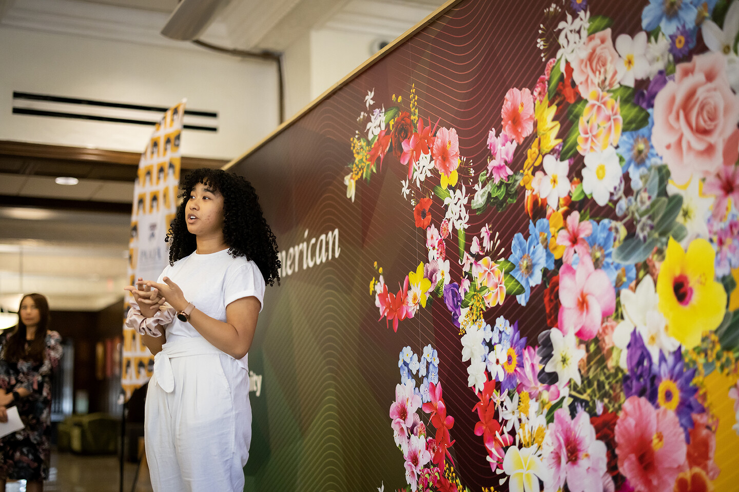 Grace Edwards speaks in front of a floral mural