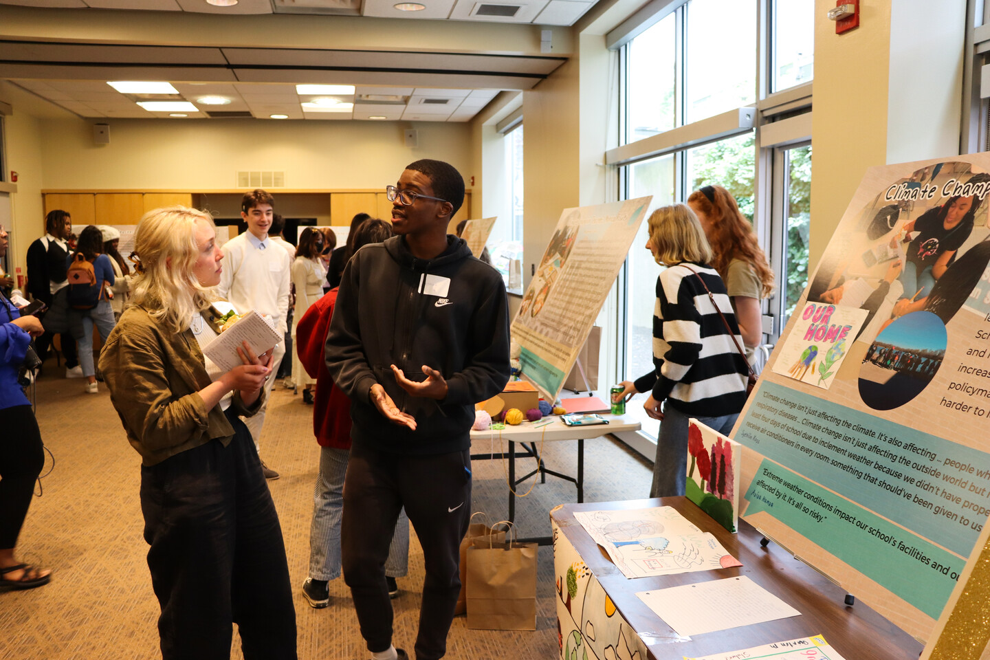 high school student speaks with a reporter about a poster presentation