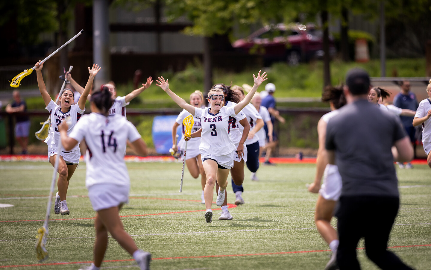 women's lacrosse players throw their hands in the air after the victory