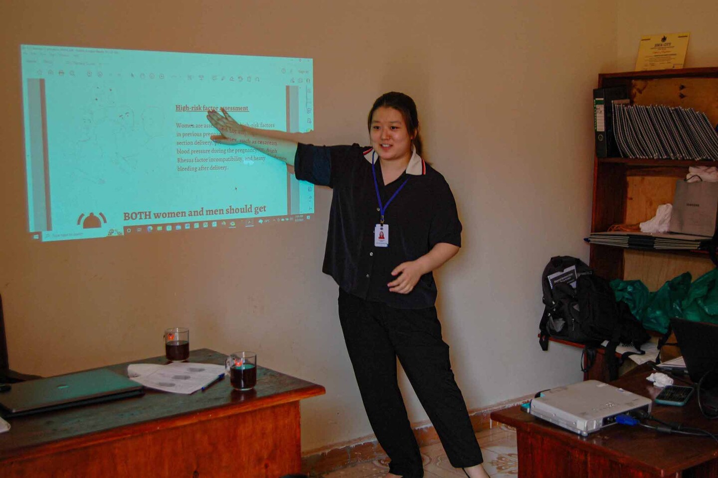 Lucy Lee points to a projected image on a wall with information about prenatal care