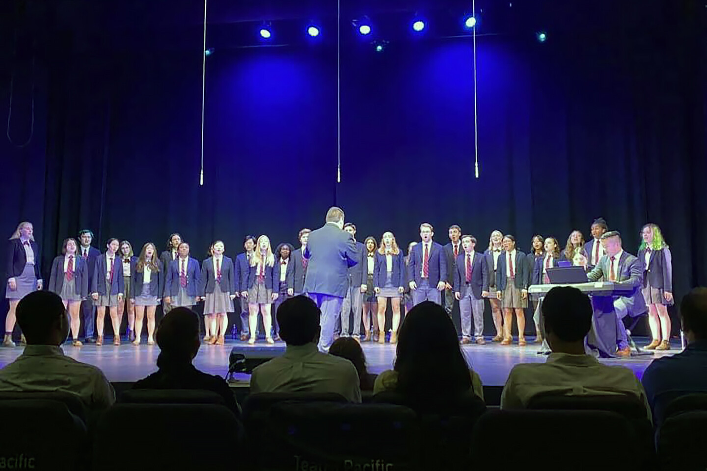 choir singing on stage with audience members in front of them