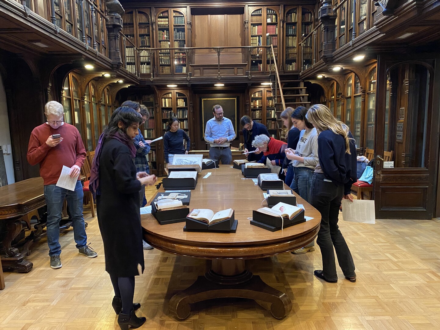 People lookiing at books on a table in a historic library. 
