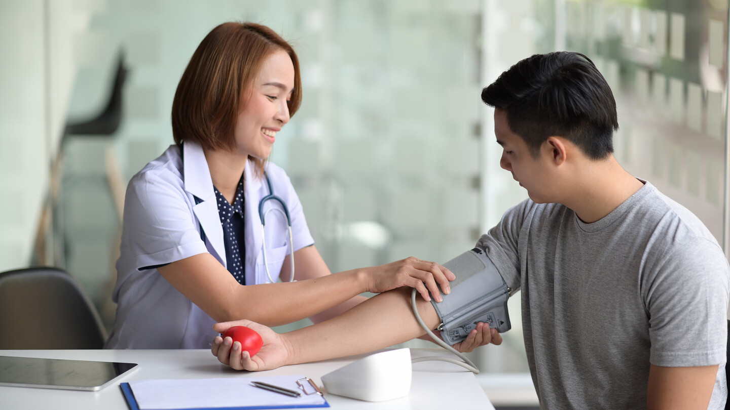 A female doctor checks a man's blood pressure.